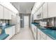 Galley-style kitchen with white cabinets and teal countertops at 410 Candlestone Ct, Spring Hill, FL 34609