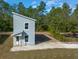 New construction home featuring a modern exterior, a minimalist front entrance, and a partially cleared lot with lots of trees at 5173 Pacific Ave, Weeki Wachee, FL 34607