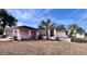 Front view of a pink house with a yard and palm trees at 6137 Mountain Way Ave, Spring Hill, FL 34608