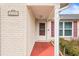 Front entrance with a red walkway, white door, and brick facade at 6333 Sutherland Ave, New Port Richey, FL 34653