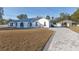 White single-story home with gray roof, paver driveway, and detached barn at 9331 Elida Rd, Spring Hill, FL 34608