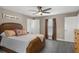 Cozy bedroom with dark ceiling fan, wood-look tile, natural light, and simple furnishings at 11160 Gyrafalcon Ave, Weeki Wachee, FL 34613