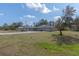 Sprawling single-story home with a long driveway, gray facade and lush lawn under a blue sky at 11160 Gyrafalcon Ave, Weeki Wachee, FL 34613