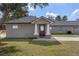 Charming single-story house featuring gray siding, a gray shingle roof, a black front door and a well-manicured green lawn at 11160 Gyrafalcon Ave, Weeki Wachee, FL 34613