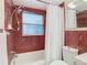 Bathroom showcasing a tub/shower combination, window, and decorative, red tiled walls at 14034 Water Tower Dr, Hudson, FL 34667