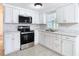 Updated kitchen with stainless steel appliances, white cabinets, and a double sink at 14034 Water Tower Dr, Hudson, FL 34667