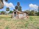 Exterior view of a wooden shed with a weathered appearance, featuring a brick planter box and a door at 14034 Water Tower Dr, Hudson, FL 34667