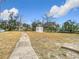 Spacious backyard showing a PODS storage unit, mature trees, and a concrete walkway at 14034 Water Tower Dr, Hudson, FL 34667