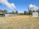 Exterior view of a grassy lot showcasing mature trees, a gray house, and a PODS storage container at 14034 Water Tower Dr, Hudson, FL 34667