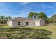 Exterior view of the house backyard featuring a grass lawn, trees, and light blue skies on a sunny day at 16434 Medley Rd, Weeki Wachee, FL 34614