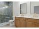 Modern bathroom with double vanity, two mirrors, lights, and tiled shower with glass door and gold trim at 16434 Medley Rd, Weeki Wachee, FL 34614