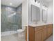 Modern bathroom with double vanity, two mirrors, lights, and tiled shower with glass door and gold trim at 16434 Medley Rd, Weeki Wachee, FL 34614