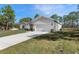 Side view of a charming single-story home featuring a long driveway and a two-car garage, surrounded by lush greenery at 16434 Medley Rd, Weeki Wachee, FL 34614