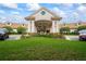 Beautiful Wellington 55+ community clubhouse featuring a manicured lawn, colorful flowers, and covered entrance at 444 Quane Ave, Spring Hill, FL 34609