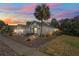 Charming single-story home with lush landscaping under a beautiful sunset sky at 444 Quane Ave, Spring Hill, FL 34609