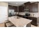 Island kitchen with dark cabinets, granite countertops, and stainless steel appliances at 6021 Wild Petunia Dr, Wimauma, FL 33598