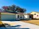 House exterior with green garage door and landscaping at 7240 Dogleg Ct, Port Richey, FL 34668