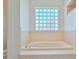 Bathroom with a bathtub, glass block window, and beige tile at 9694 Southern Belle Dr, Weeki Wachee, FL 34613