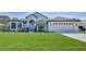 Single-story home with a two-car garage and lush green lawn at 9694 Southern Belle Dr, Weeki Wachee, FL 34613