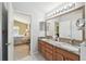 Bright bathroom with a double sink, a large mirror, and the bedroom in the background at 11637 Spindrift Loop, Hudson, FL 34667