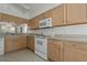Functional kitchen with light wood cabinetry, white appliances, and tile flooring at 11744 Wheatfield Loop, Hudson, FL 34667