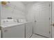 Functional laundry room with a white washer, dryer, overhead shelf, and a door at 11744 Wheatfield Loop, Hudson, FL 34667