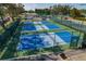 Aerial view of fenced pickleball courts with blue playing surfaces at 11744 Wheatfield Loop, Hudson, FL 34667