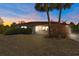 Single-story house with a brown roof, light-colored walls, and a small porch at dusk at 12417 Shafton Rd, Spring Hill, FL 34609