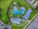 Aerial view of a community pool with palm trees, lounge chairs, and a modern clubhouse in a green neighborhood at 14855 Renaissance Ave, Odessa, FL 33556