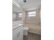 Bathroom featuring a white vanity with an inset sink and a shower-tub combo with marbled tile surround at 15111 Peach Bloom Rd, Brooksville, FL 34614