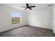 Bright bedroom features a ceiling fan, window with a scenic view, and modern gray flooring at 15111 Peach Bloom Rd, Brooksville, FL 34614