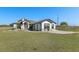 Charming single-story home with a well-manicured lawn and a classic design under a clear blue sky at 15111 Peach Bloom Rd, Brooksville, FL 34614