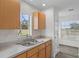 A well-lit sink beneath a window in a bright kitchen with natural-tone cabinets and white countertops at 15111 Peach Bloom Rd, Brooksville, FL 34614