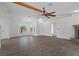 Large living area with white walls, gray floors, a stone fireplace, and a beamed ceiling at 15111 Peach Bloom Rd, Brooksville, FL 34614