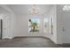 Bright living room featuring modern light fixture, gray floors, white walls, and multiple large windows at 15111 Peach Bloom Rd, Brooksville, FL 34614