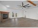 Spacious living room features gray floors, a stone fireplace, and a ceiling fan at 15111 Peach Bloom Rd, Brooksville, FL 34614