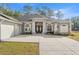 The front of a single-story home with a spacious concrete driveway and elegant architectural details at 7482 Winter St, Brooksville, FL 34613
