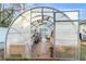 Interior of greenhouse with open door, wooden floors and shelving with various plants and accessories at 7482 Winter St, Brooksville, FL 34613