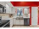 Modern kitchen with white cabinets, stainless steel appliances, and a red accent wall at 8434 Hazelton St, Spring Hill, FL 34608