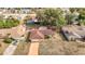 An aerial view showcasing a brick home with a driveway, mature trees, and neighborhood at 8464 Dirlenton Way, Weeki Wachee, FL 34613