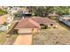 Aerial view of a brick home with a driveway and mature trees in a residential neighborhood at 8464 Dirlenton Way, Weeki Wachee, FL 34613