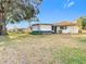 A home's grassy backyard on a sunny day with white exterior and a screen porch at 8464 Dirlenton Way, Weeki Wachee, FL 34613