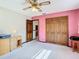 Bedroom with a light pink accent wall, wooden closets and a ceiling fan at 8464 Dirlenton Way, Weeki Wachee, FL 34613