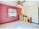 Bright bedroom featuring neutral carpet, a pink accent wall and ceiling fan at 8464 Dirlenton Way, Weeki Wachee, FL 34613