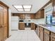 A kitchen with wood cabinets, a white refrigerator and oven, and a skylight at 8464 Dirlenton Way, Weeki Wachee, FL 34613