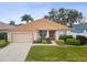 Charming single-story home featuring a manicured lawn, complemented by a bright red front door and beige exterior at 8709 Maple Pond Ct, Trinity, FL 34655