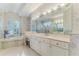 Bright bathroom features dual vanities, tiled floors, and a relaxing tub with shuttered windows at 9091 Alexandria Dr, Weeki Wachee, FL 34613