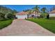 Expansive brick driveway leads to this home with lush landscaping and a two-car garage at 9091 Alexandria Dr, Weeki Wachee, FL 34613