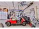 View of a well-organized garage with ample storage space and a red golf cart inside at 9091 Alexandria Dr, Weeki Wachee, FL 34613
