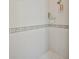 Shower featuring white tile with a decorative border and an organized shower caddy at 9091 Alexandria Dr, Weeki Wachee, FL 34613